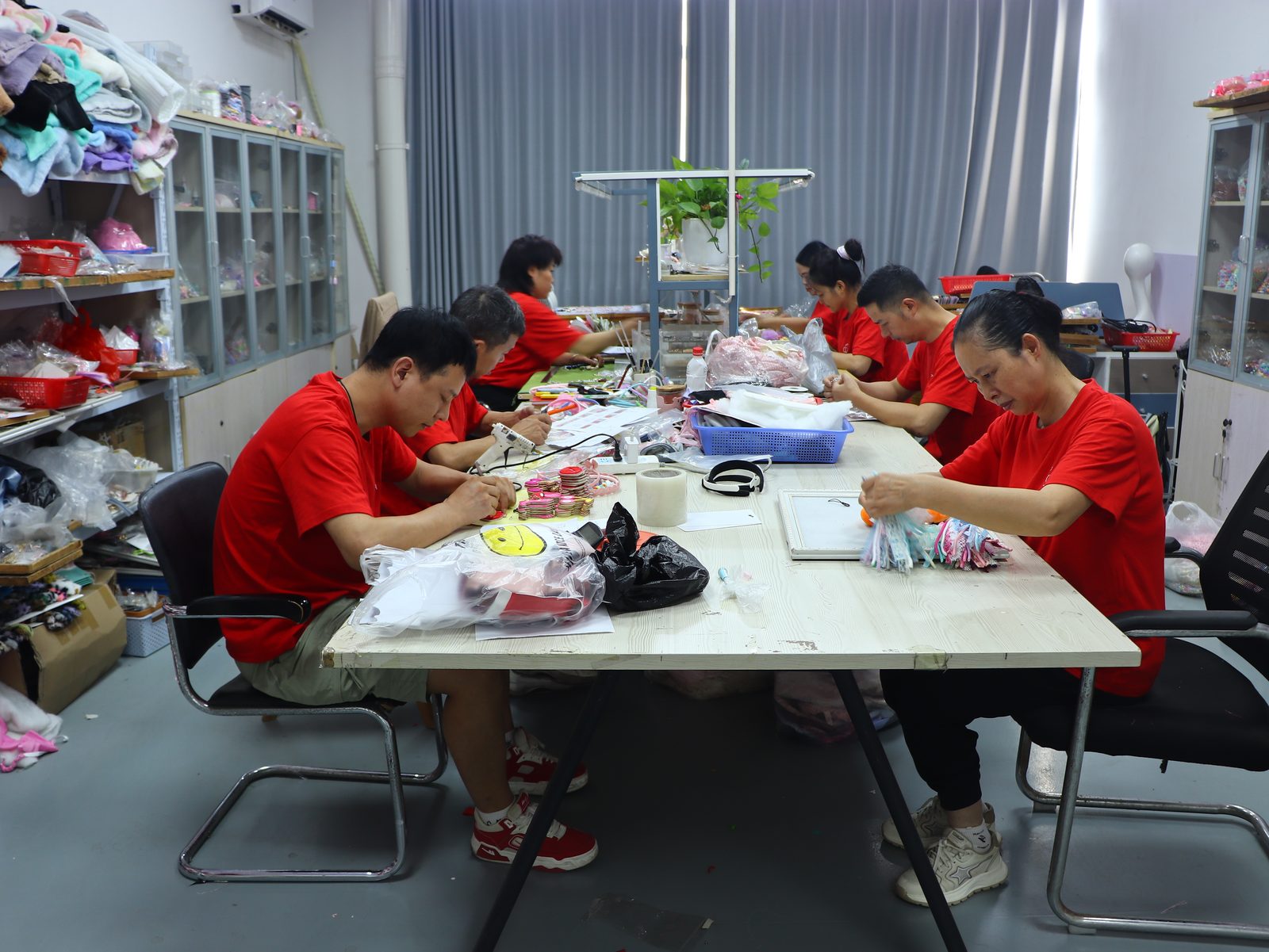 Hand assembly workshop — workers assembling charm pendants with chains and clasps