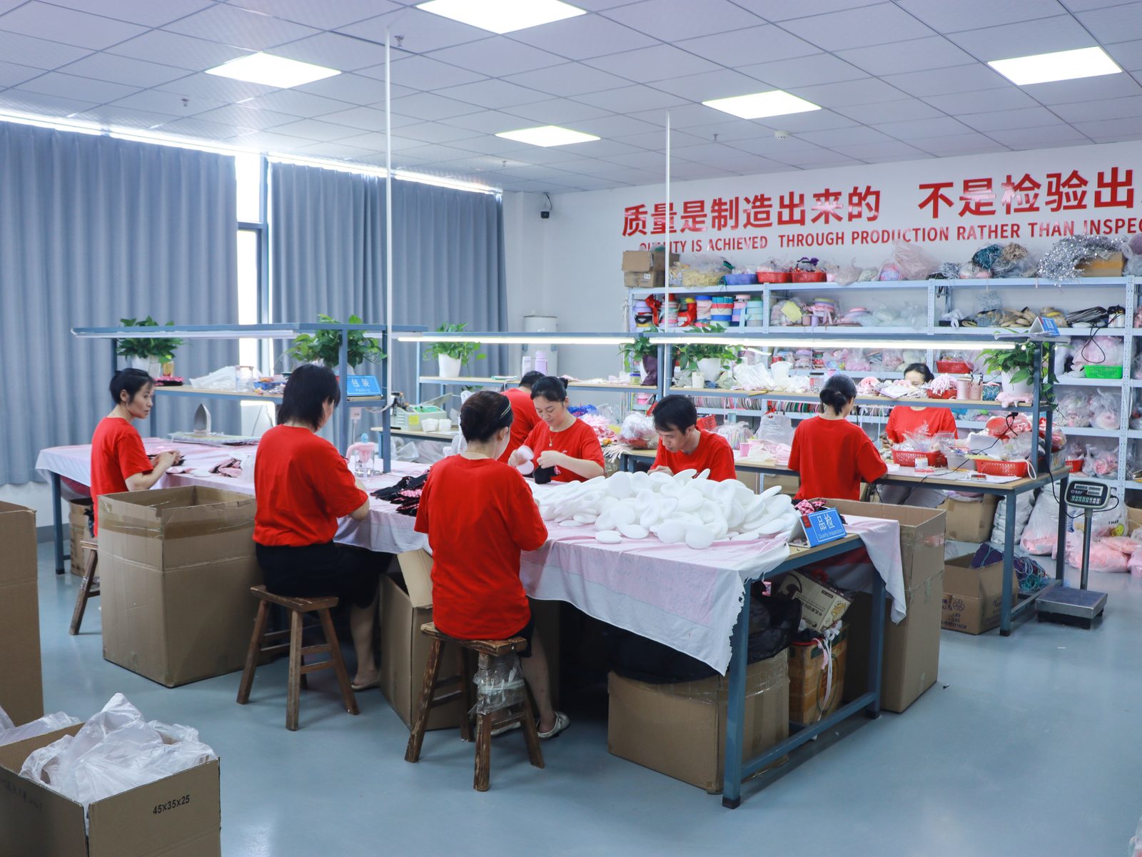 Packaging and final QC area — workers carding and boxing wholesale charms