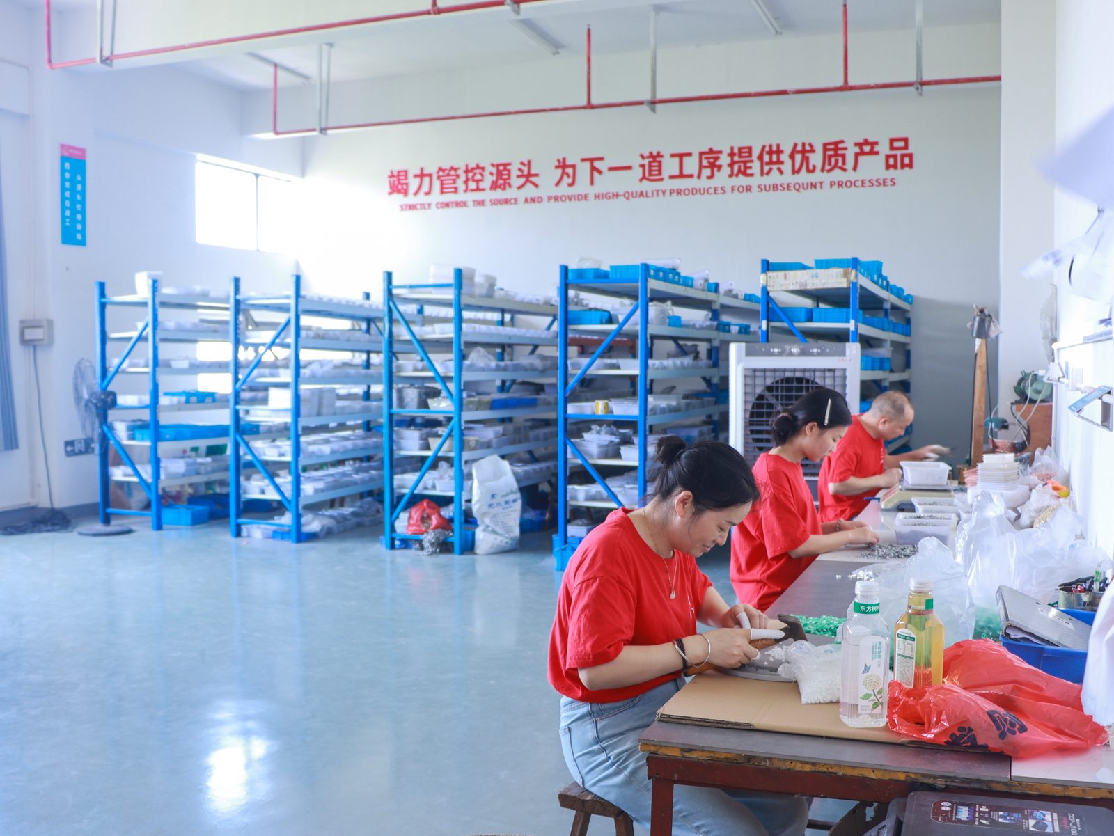 Quality source control — workers performing detailed hand finishing on charm pendants